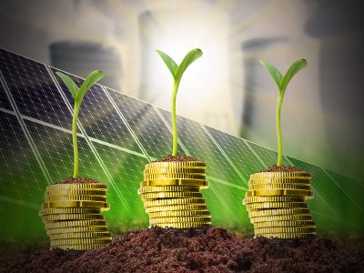 Golden coins with solar panels and nuclear power plant on a background.